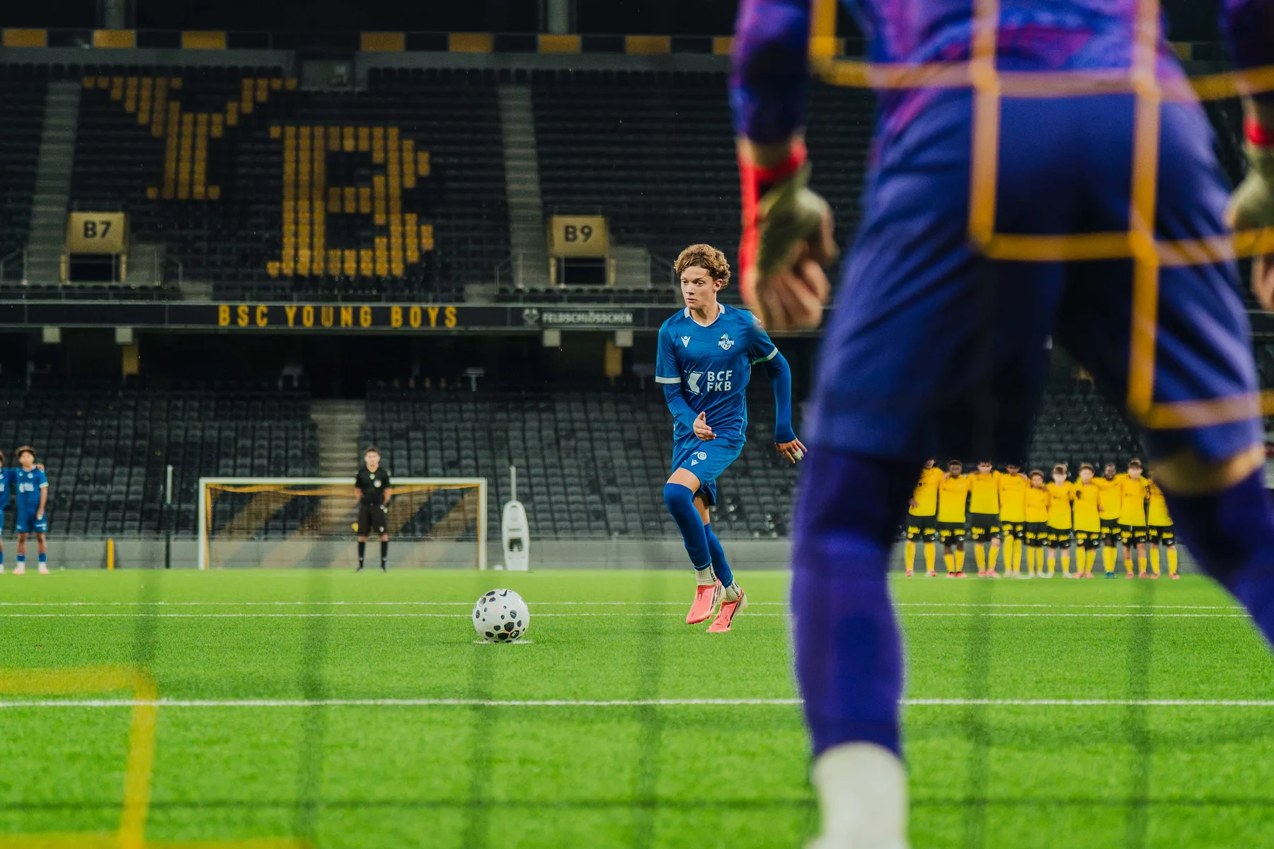Blick durchs Tornetz auf das Spielfeld und die YB-Tribüne