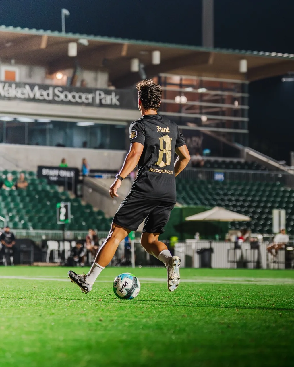 Spieler von hinten mit Ball vor der Tribüne
